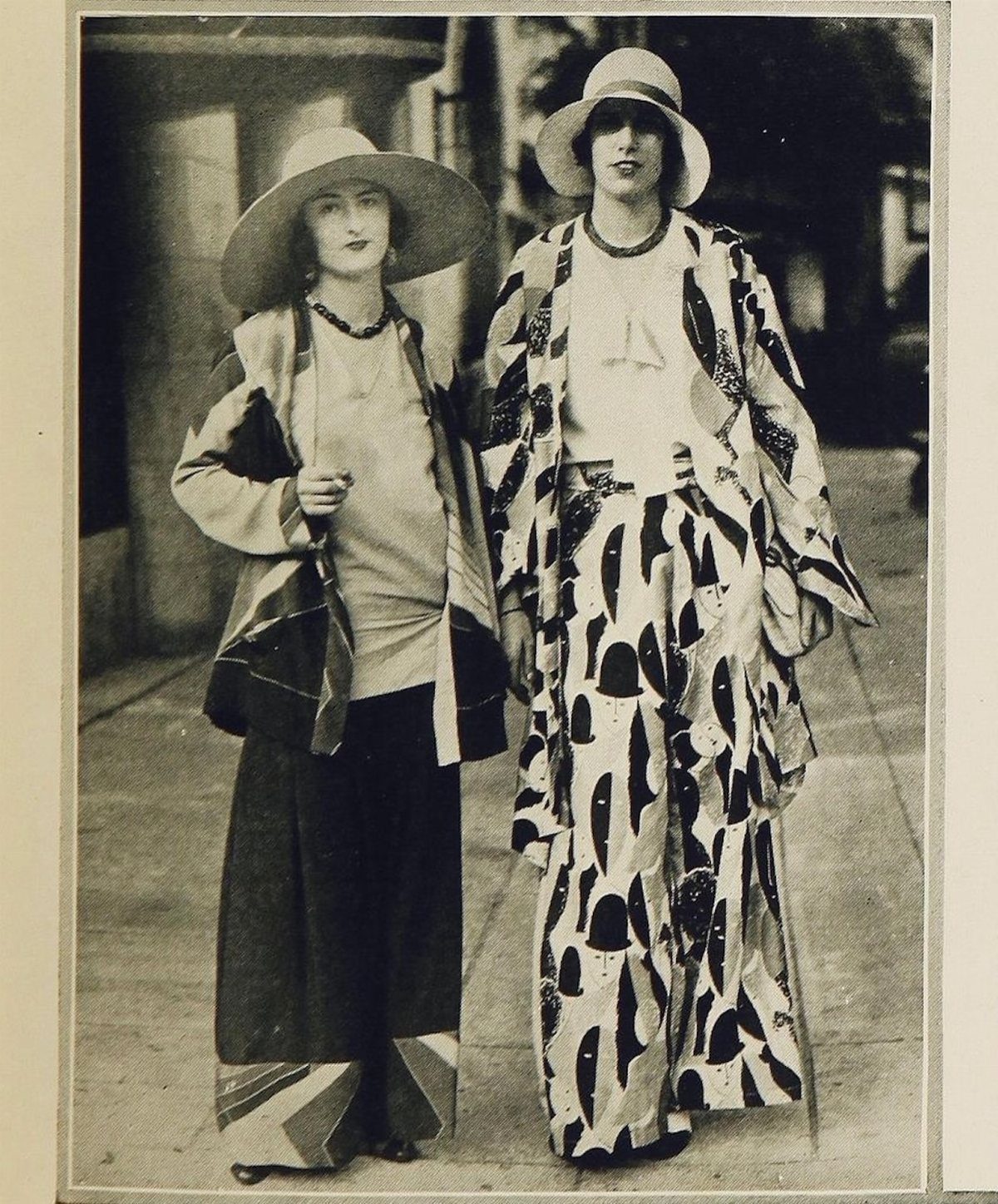 Two women standing in 1920s patterned beach pajamas and wide-brimmed hats.