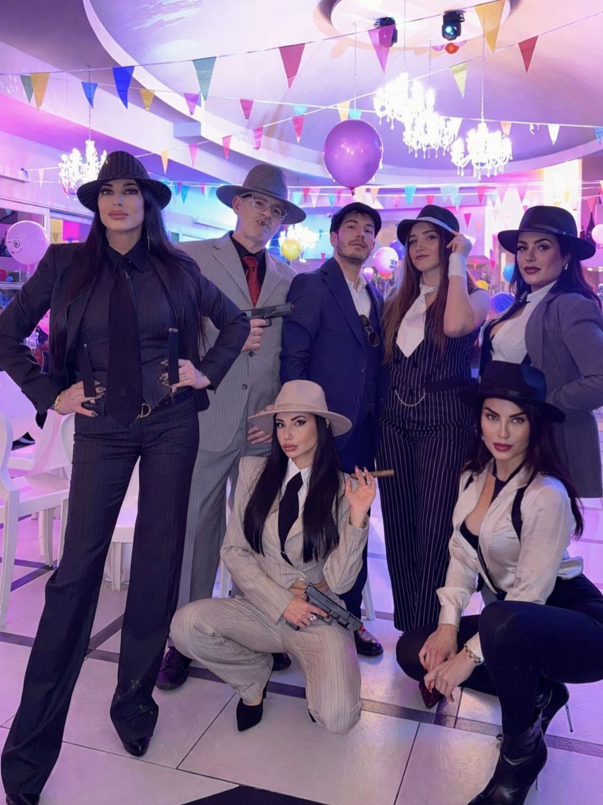 People dressed in 1920s gangster and flapper style costumes posing together in a decorated room.