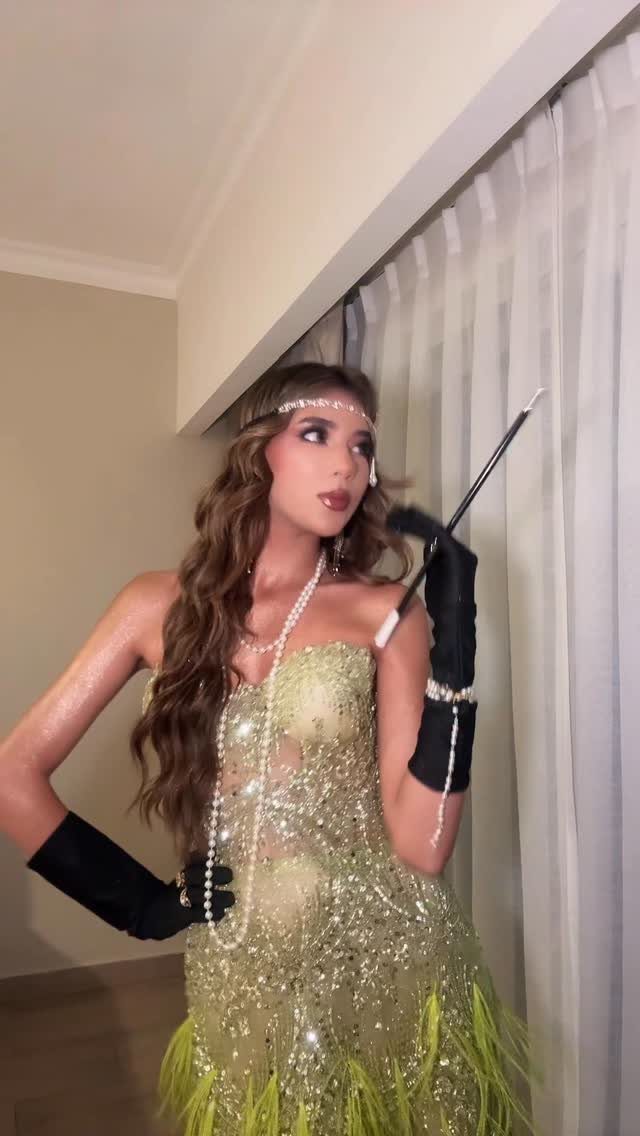 Woman in a sparkling lime green sequined dress with feather trim and black gloves.