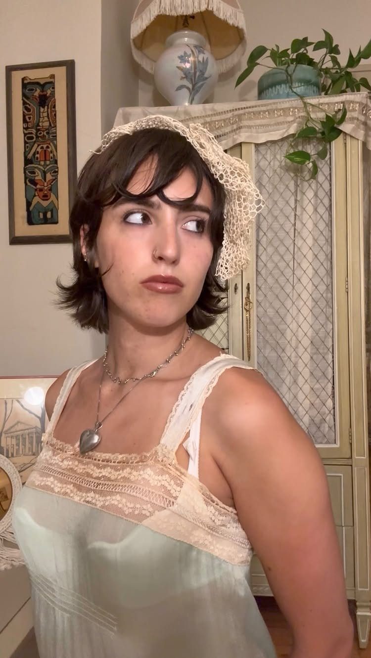 Woman in a vintage lace slip dress and headpiece looking sideways.