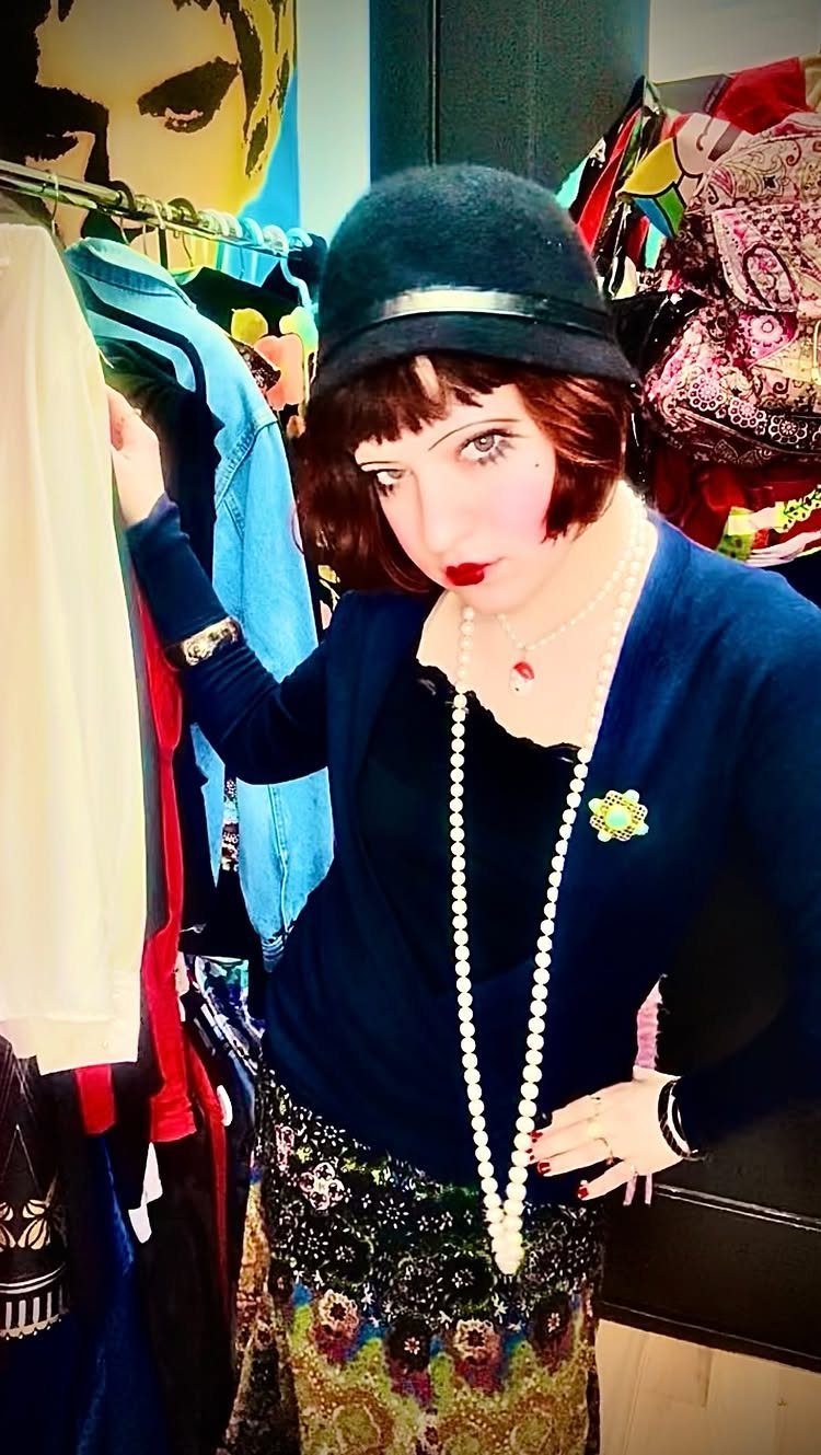 Woman in 1920s style clothing including a cloche hat and long pearl necklaces.