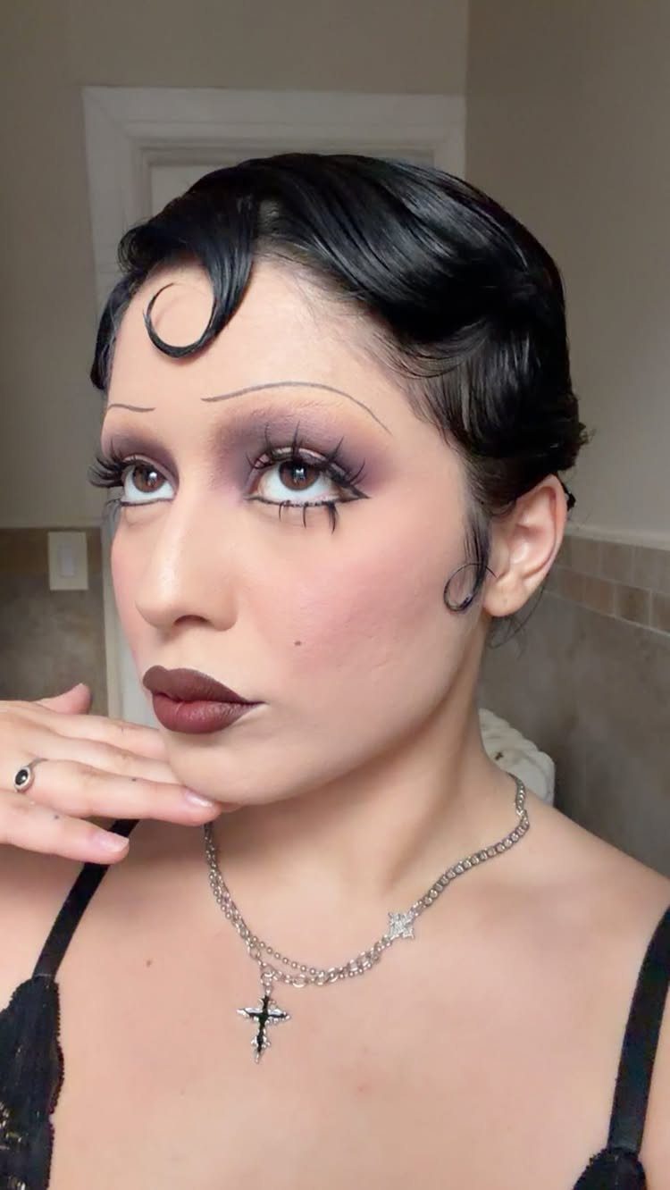 Woman with finger wave hair, thin eyebrows, and dark vintage-style makeup looking away.