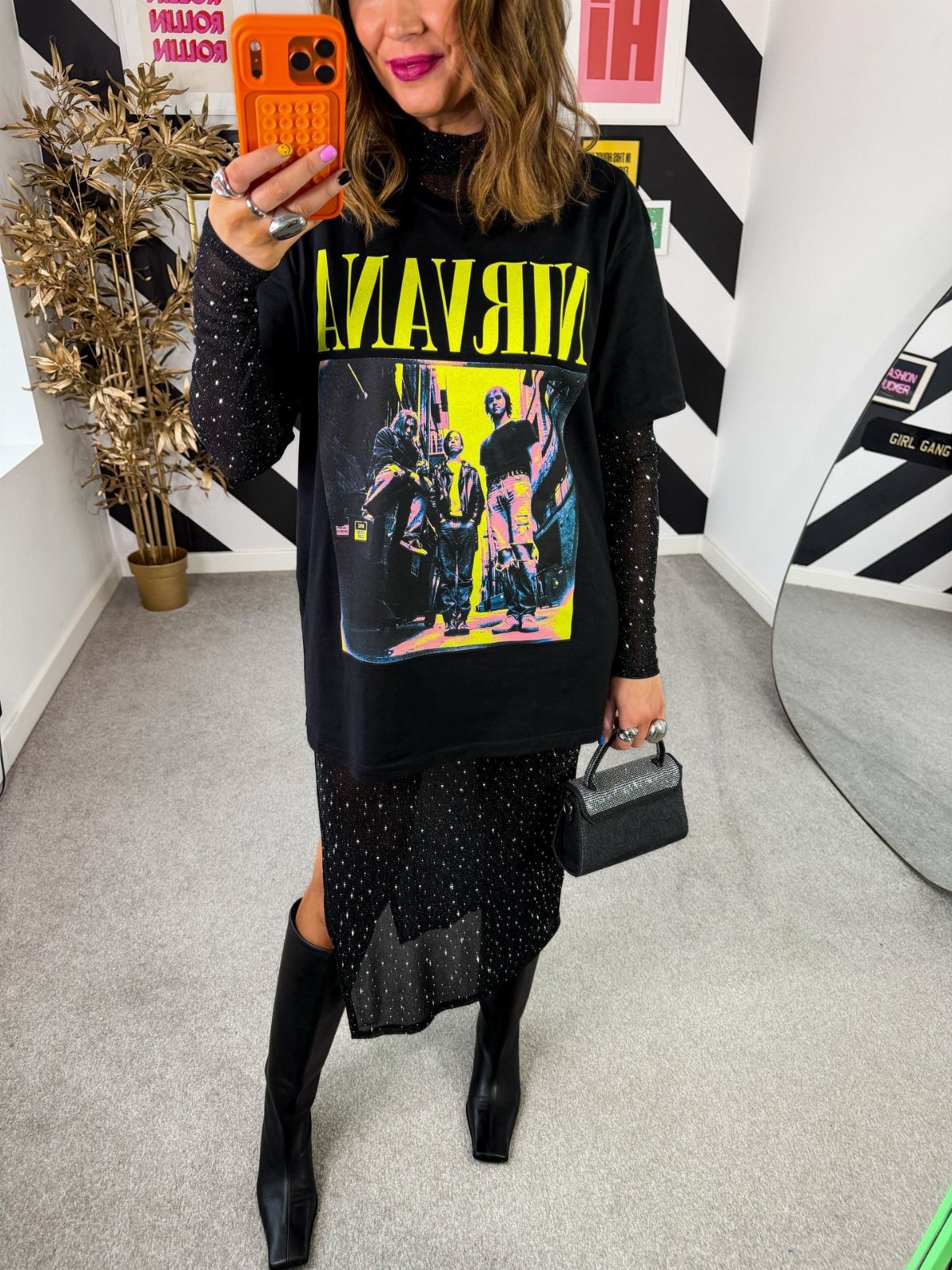 Woman in a Nirvana graphic tee, sparkly mesh layers, and black boots posing for a selfie.