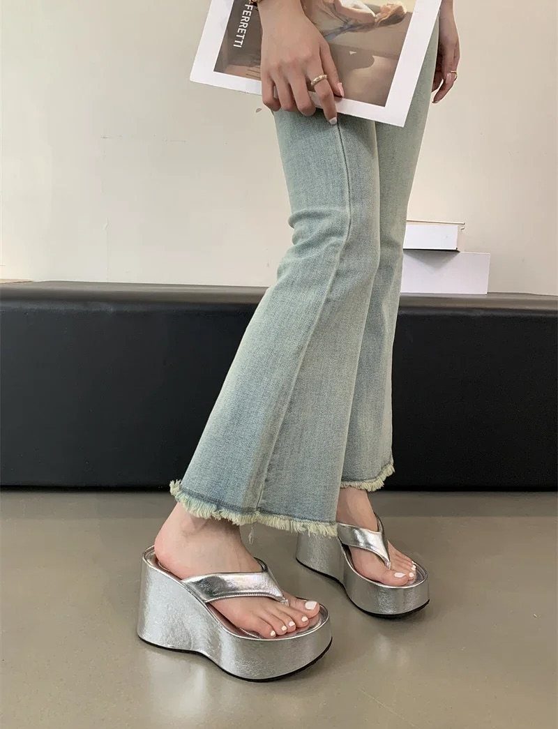 Silver metallic platform wedge sandals worn with light blue flared denim jeans.