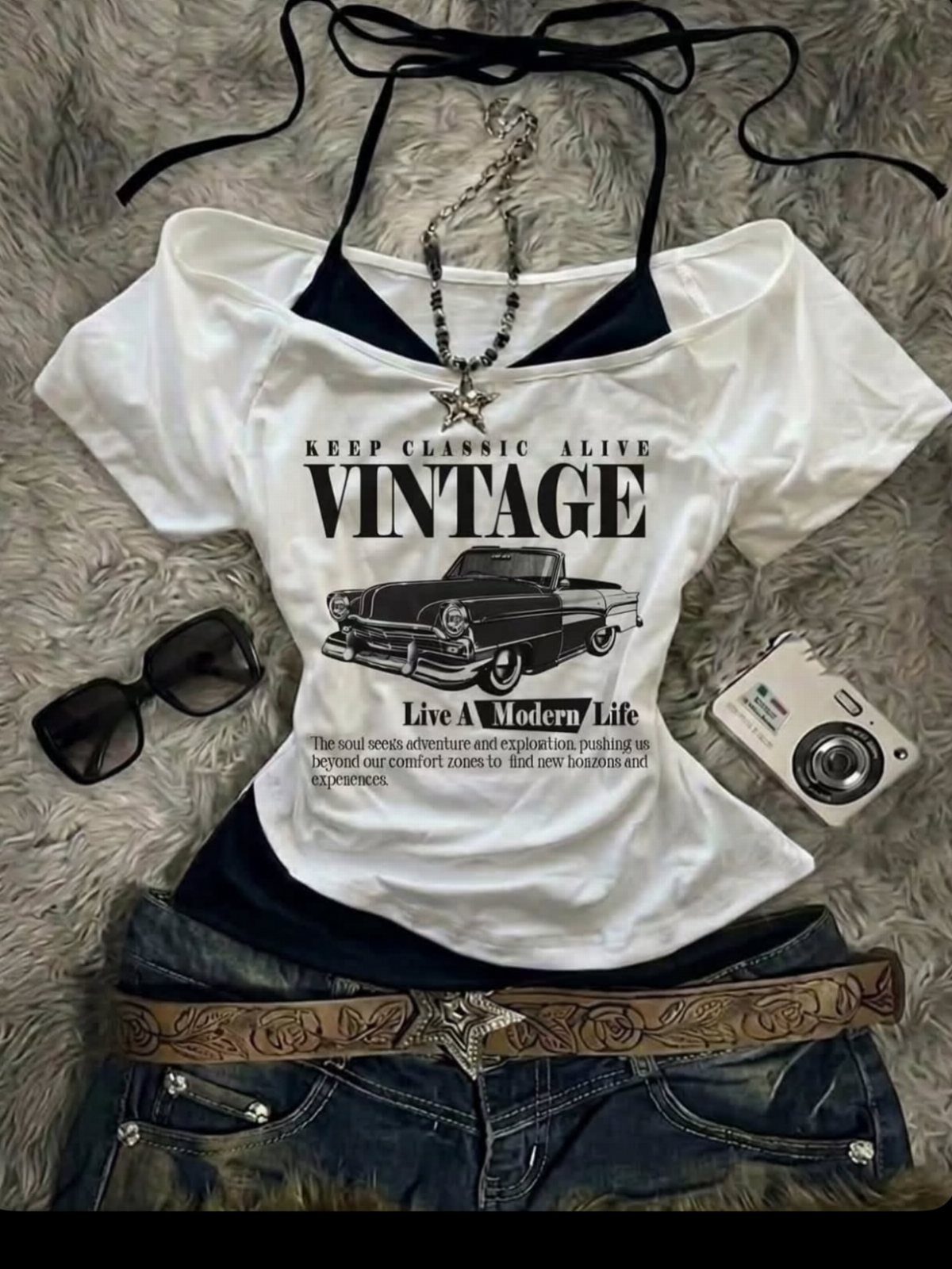 White graphic t-shirt with a vintage car print, denim shorts, sunglasses, and a digital camera.