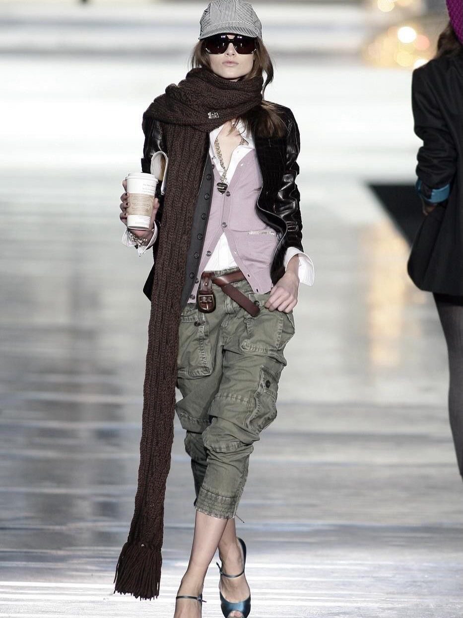 Woman walking a runway in a layered outfit with cargo pants and a long scarf.