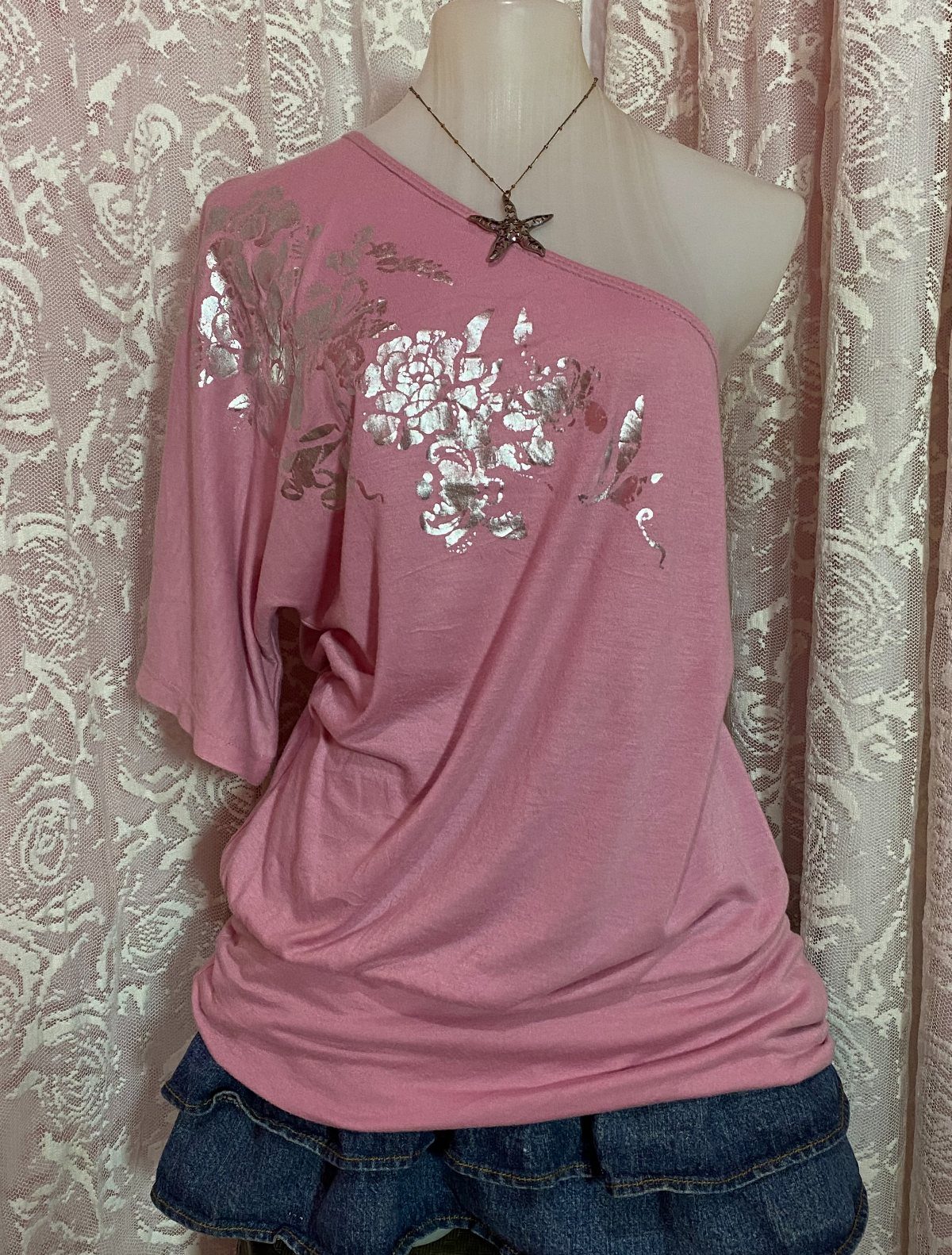 Pink one-shoulder top with silver floral designs and a denim ruffled skirt on a mannequin.