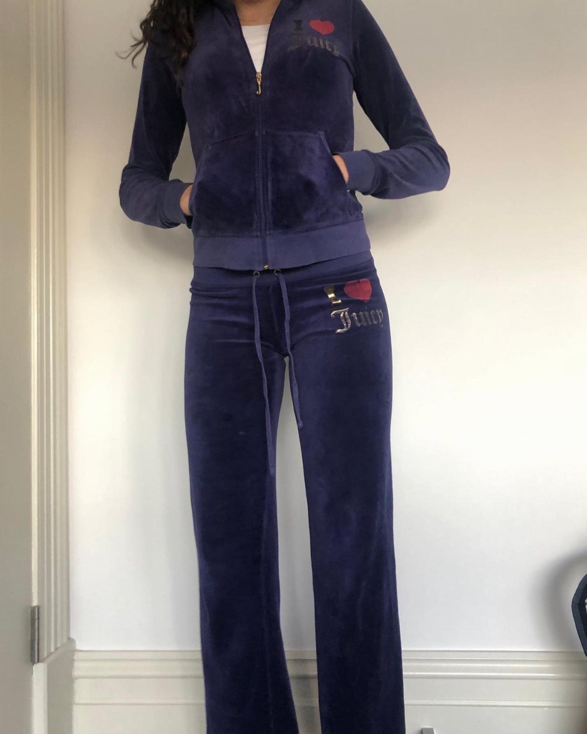 A person wearing a navy blue velour zip-up hoodie and matching flared tracksuit pants.
