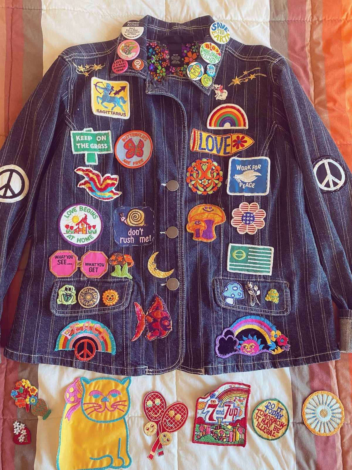 A dark blue denim jacket covered in many colorful embroidered patches and pins.