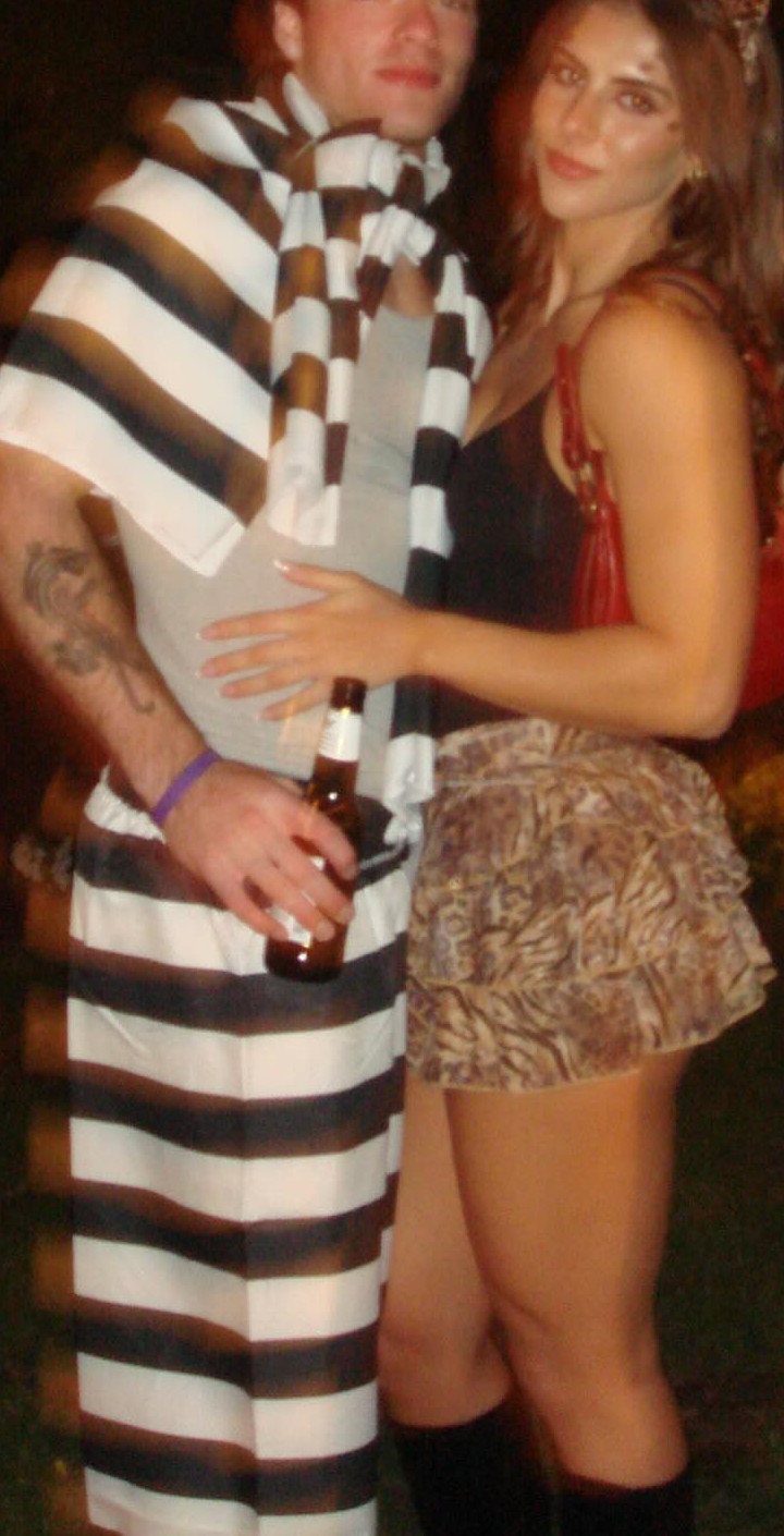 A man in a striped prisoner costume and a woman in animal print shorts posing together.