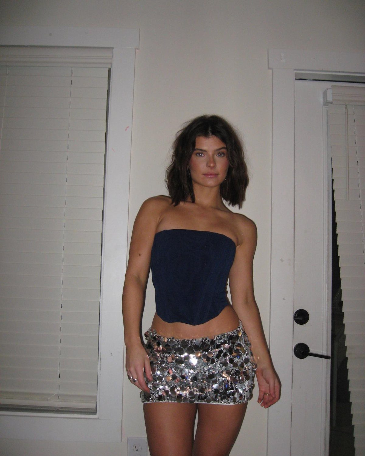 A woman wearing a navy strapless top and a silver sequined mini skirt.