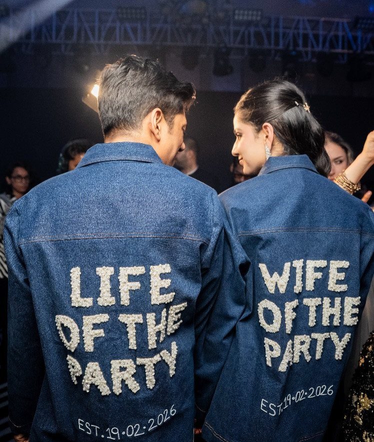 Man and woman wearing matching denim jackets with Life of the Party text on their backs.