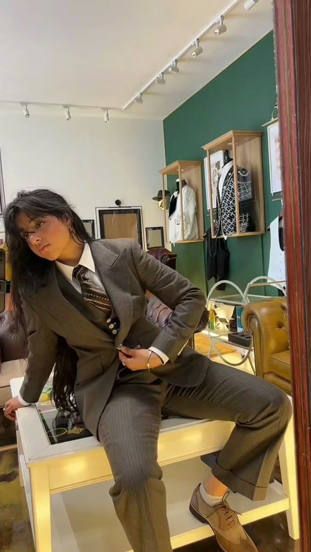 A woman wearing a vintage brown pinstripe suit and tie posing in a room.