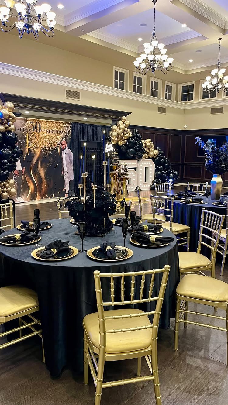 Decorated banquet hall with black and gold themed tables, chairs, and balloons for a 50th birthday.