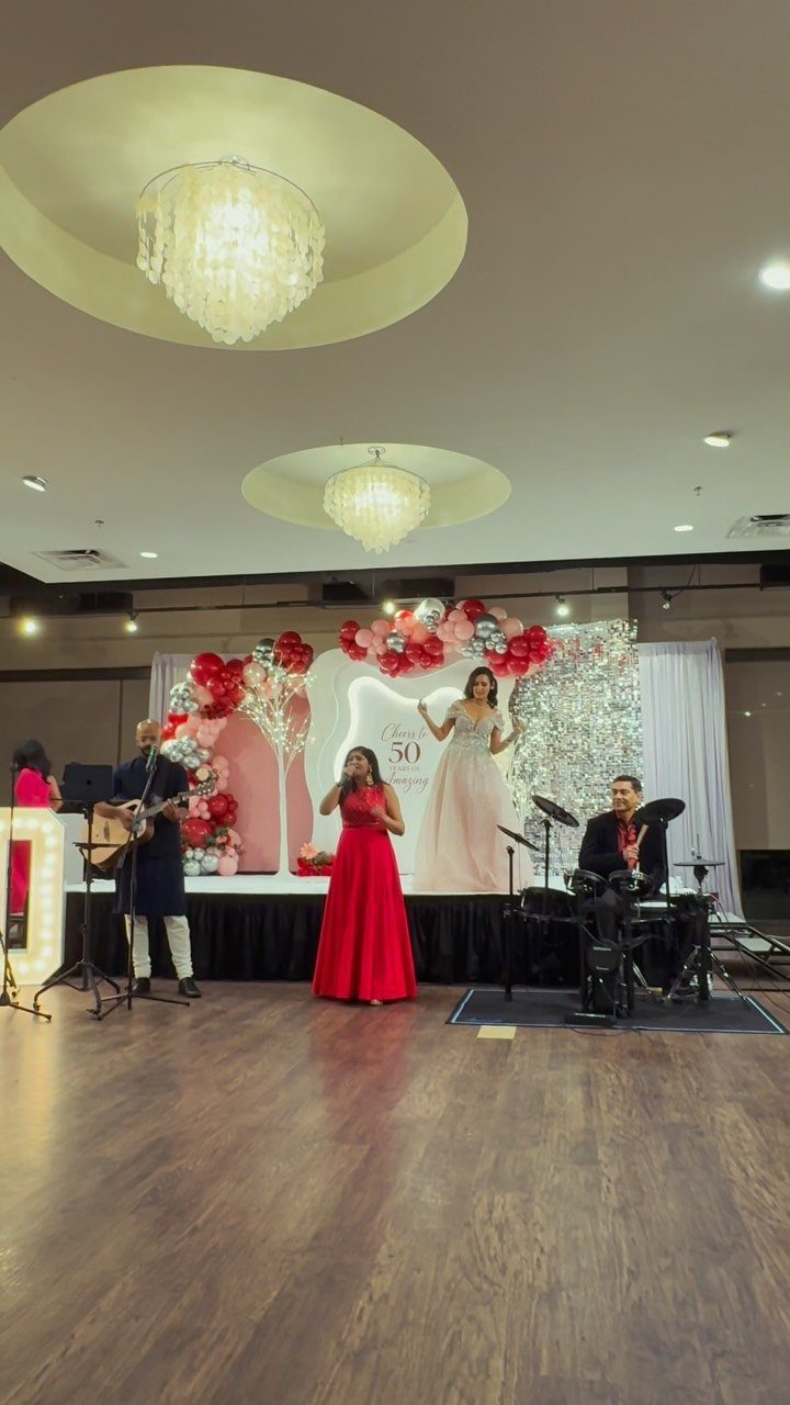 A guitarist and a singer performing on a decorated stage with pink balloons.