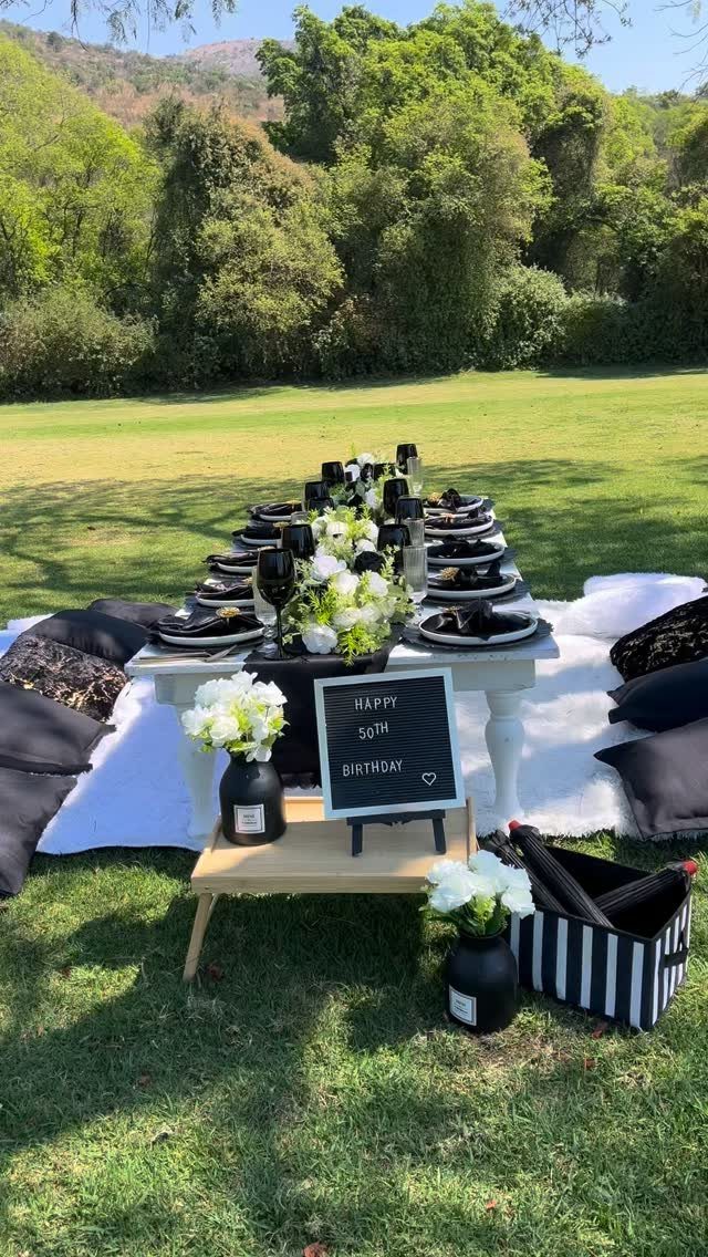 A decorated outdoor dining table with white flowers and a Happy 50th Birthday sign.
