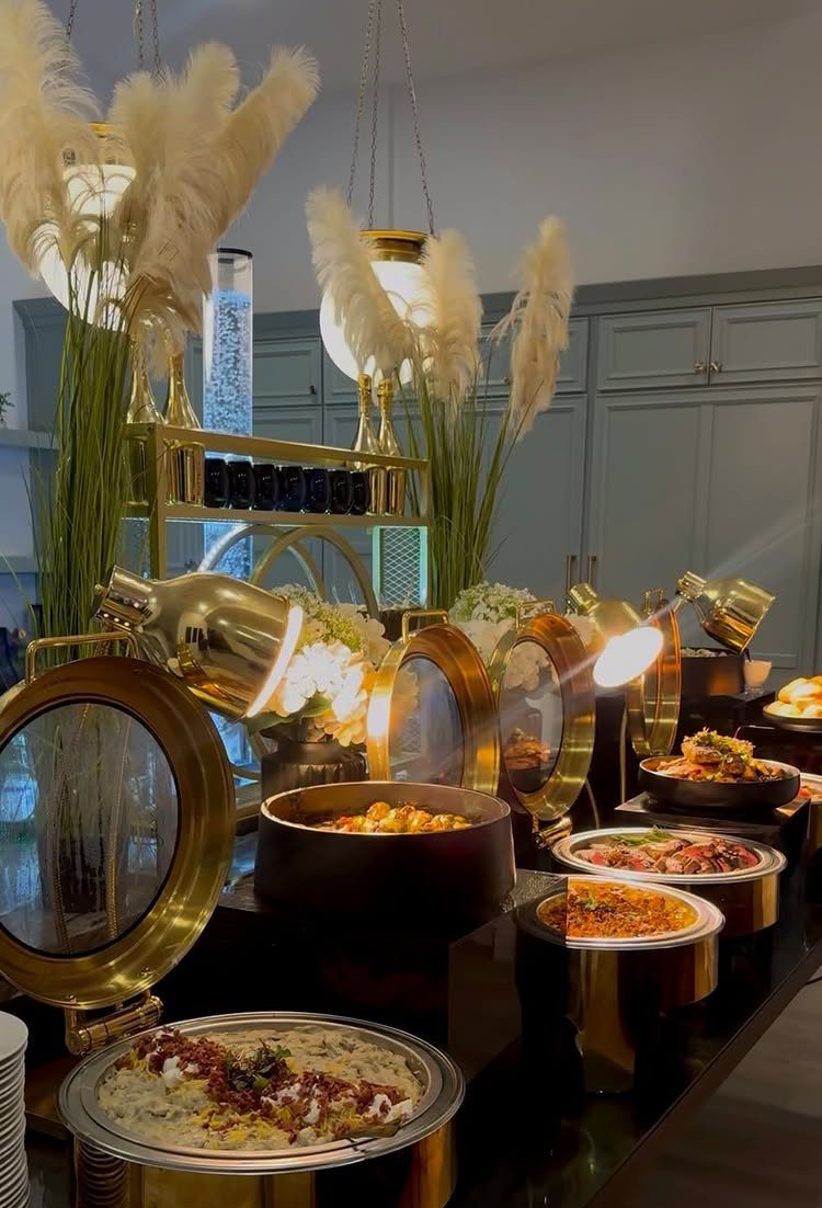 Gold chafing dishes filled with various warm foods arranged on a decorated buffet table.