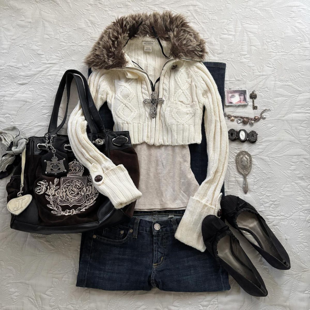 White cable-knit cropped cardigan with faux fur collar laid with denim shorts and accessories.