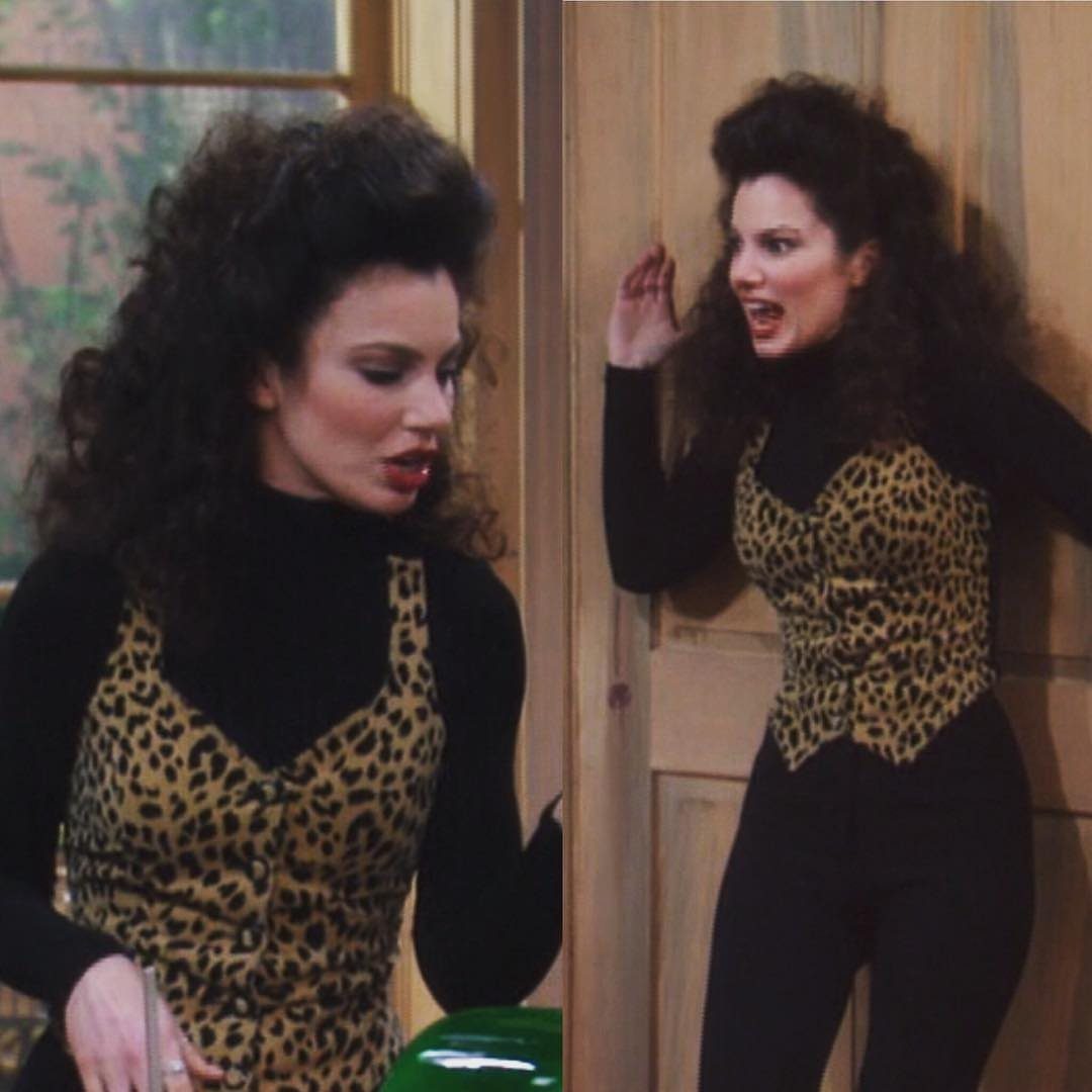 Two women with big hair wearing leopard print vests over black turtlenecks.