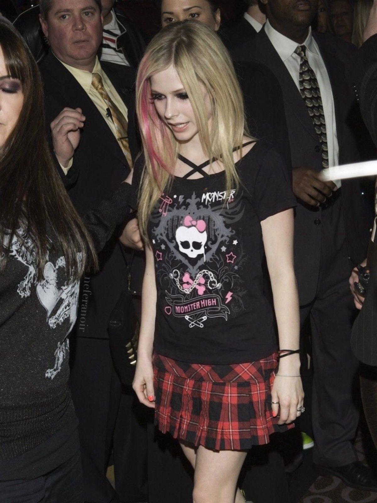 Blonde woman wearing a black Monster High graphic t-shirt and a red plaid mini skirt.