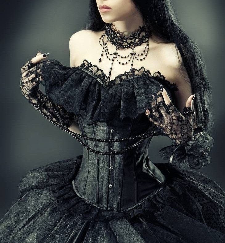 A person wearing a black lace top, structured corset, and voluminous lace skirt.