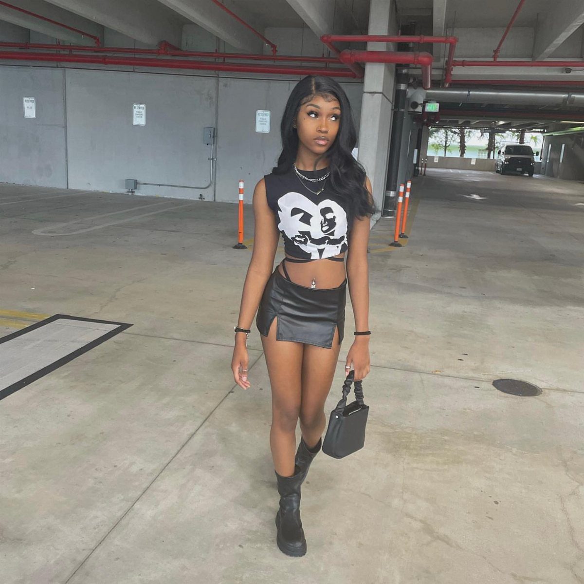 A woman wearing a black graphic tank top and a black leather mini skirt.