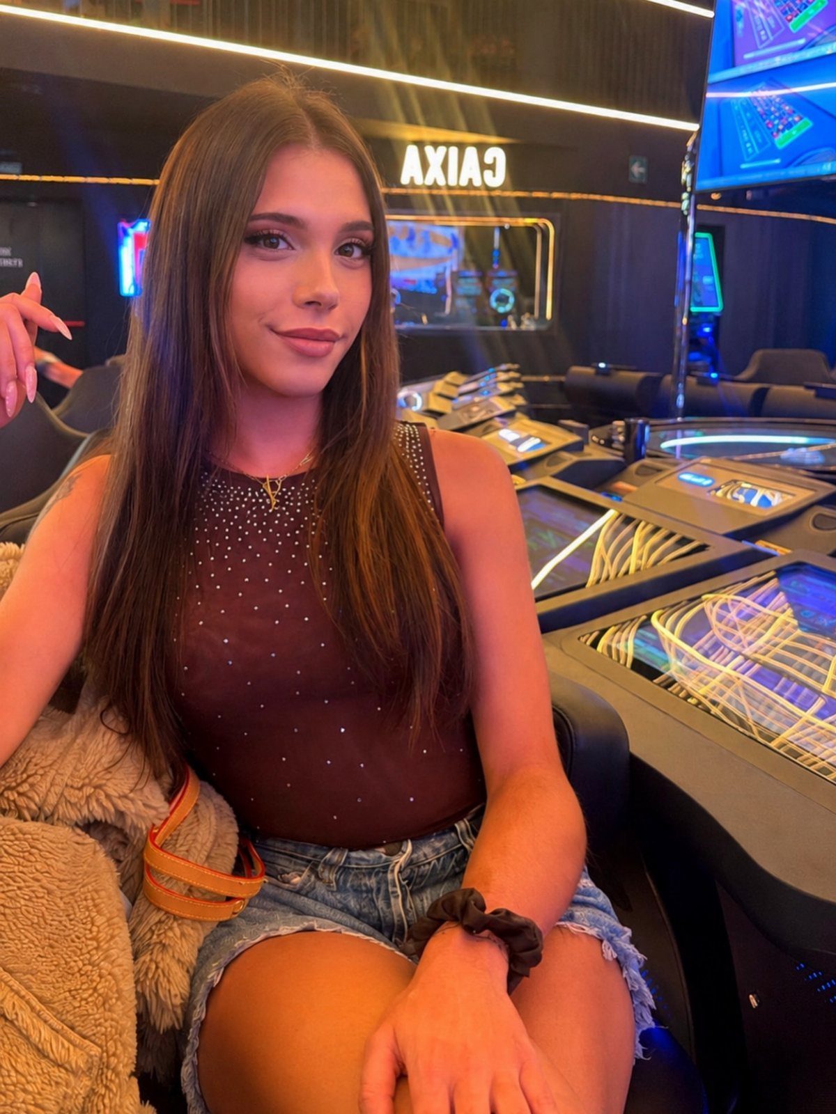 Young woman in a rhinestone-embellished dark top sitting in a casino setting.