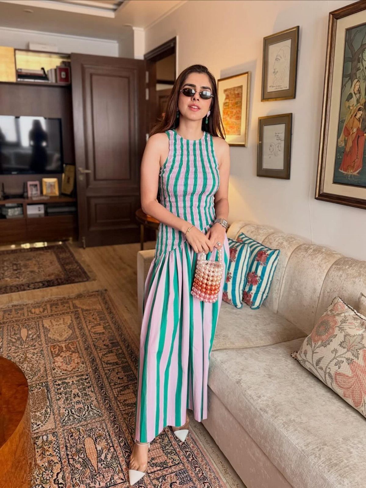 Woman in a teal and white striped sleeveless maxi dress standing in a living room.