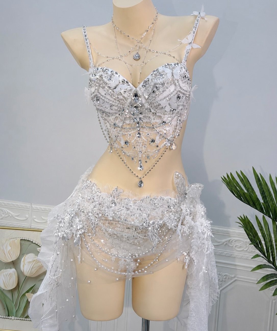 A white mannequin wearing a sparkling silver and white crystal-encrusted rave outfit.