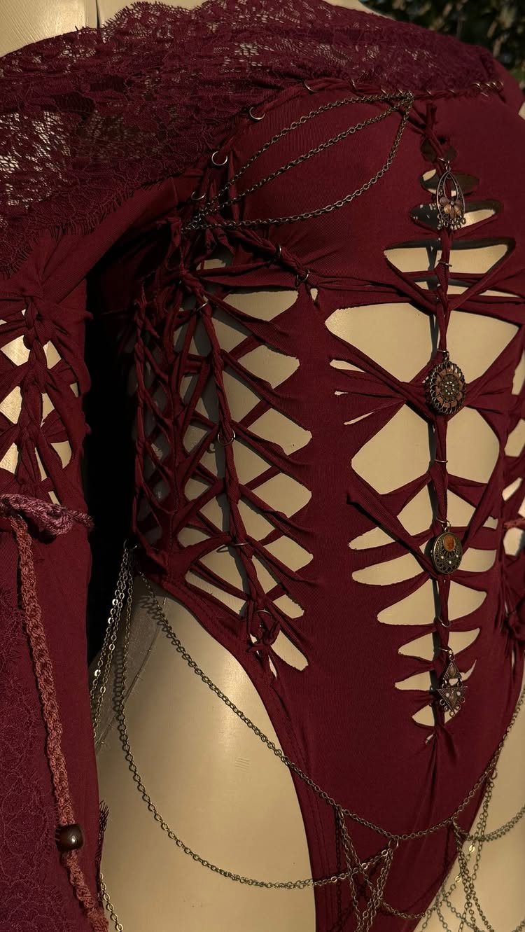 Maroon lace bodysuit with lattice cutouts and silver chain embellishments on a mannequin.