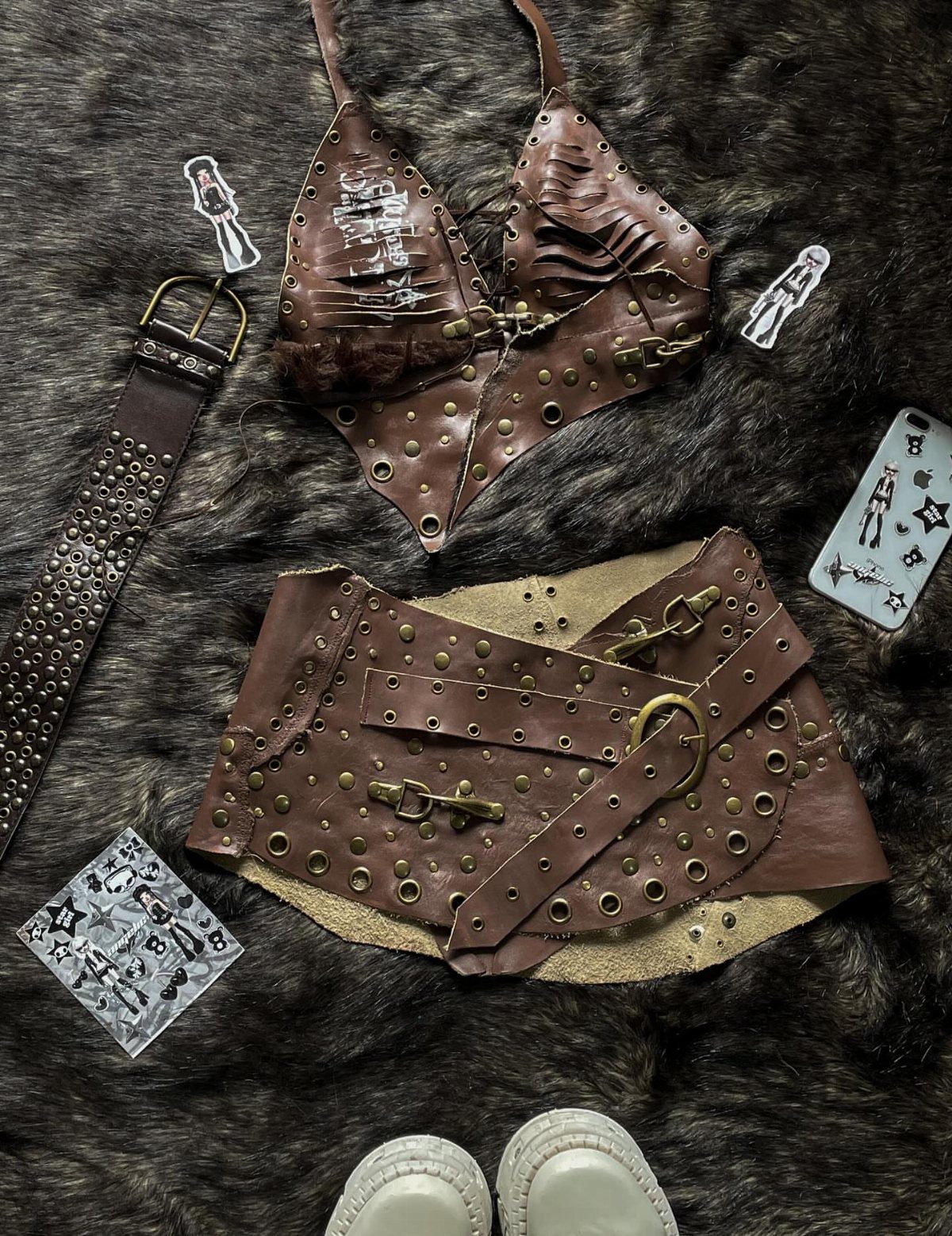 Brown leather studded halter top and matching skirt laid on dark faux fur.