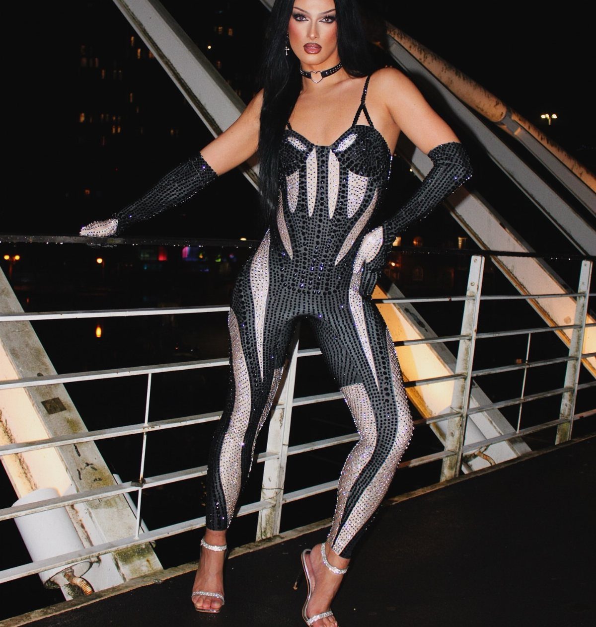 A person posing in a sparkling black and silver sequined catsuit and matching gloves.