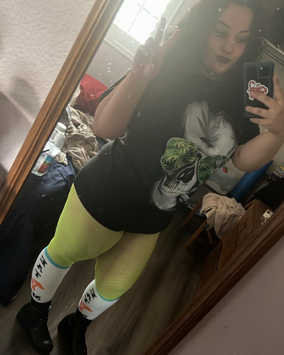 A person posing in a skull t-shirt, lime green leggings, and patterned socks.