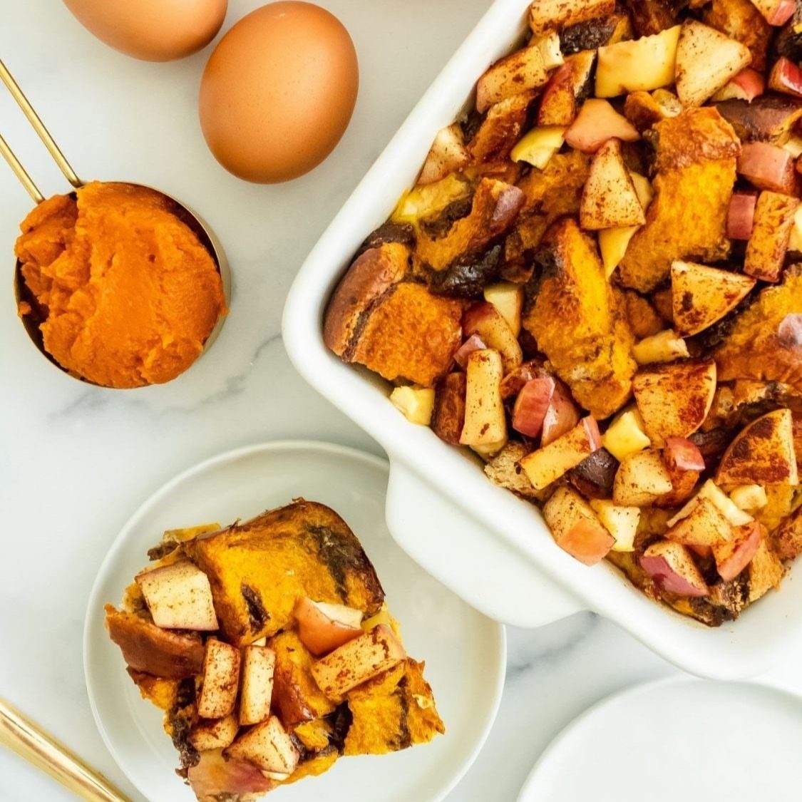 Pumpkin bread pudding with diced apples in a white dish and on a small plate.