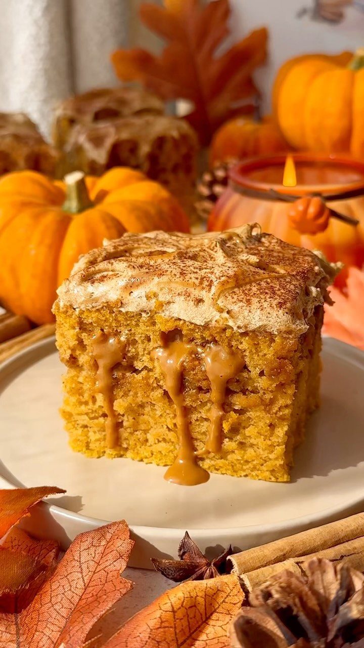 A slice of pumpkin cake with caramel sauce dripping down onto a white plate.