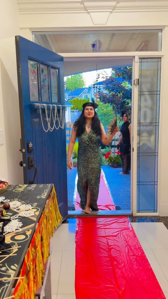 Woman wearing a sparkling green sequined flapper dress standing in a doorway on a red carpet.