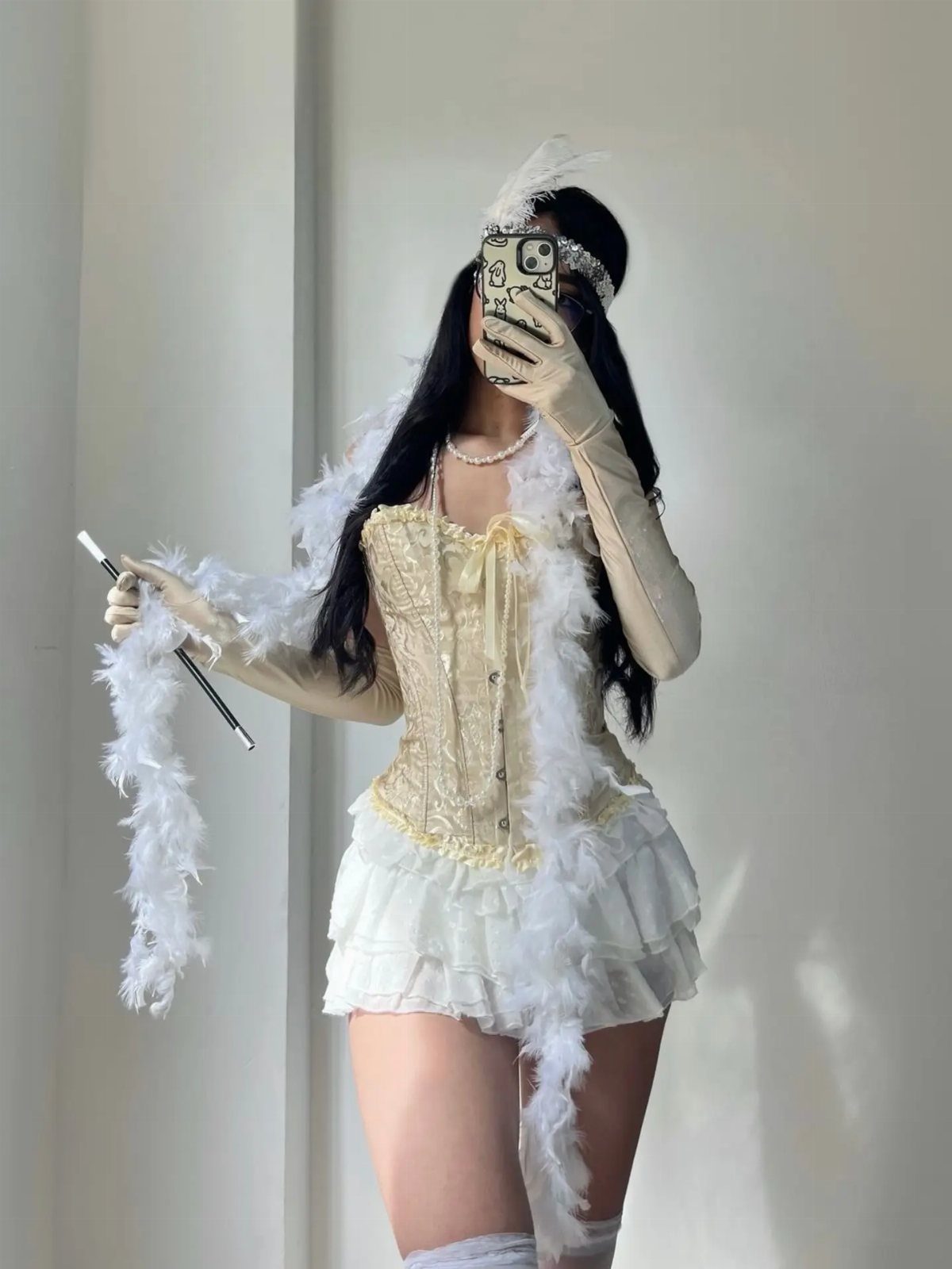 A person wearing a cream flapper costume with a feather boa and long gloves.