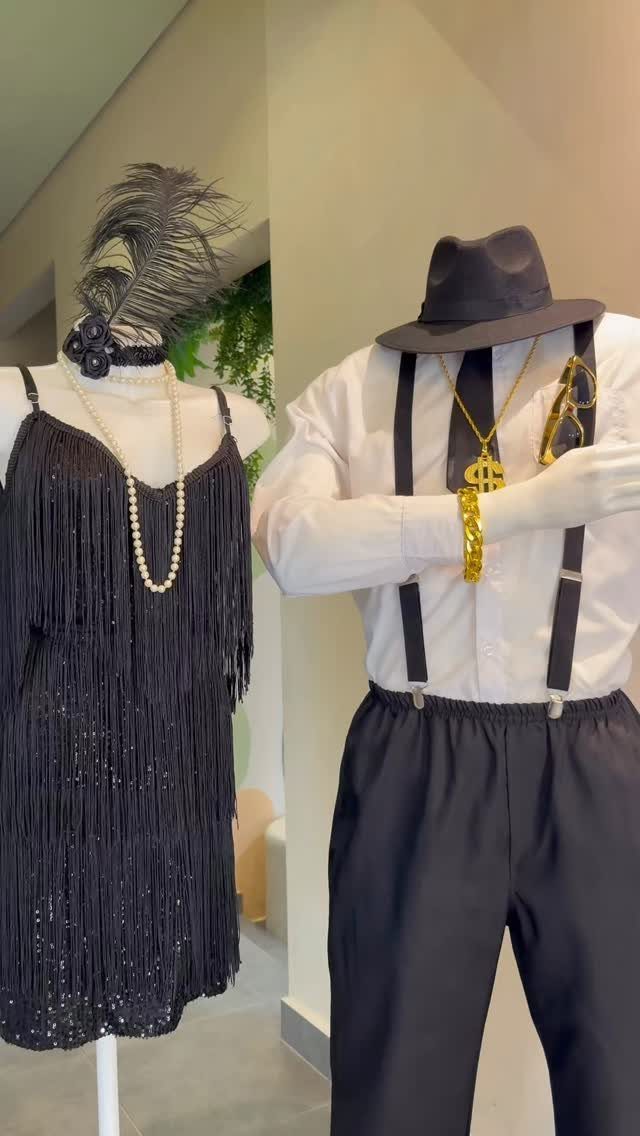 Mannequins wearing black flapper dress and 1920s menswear with suspenders and a fedora.