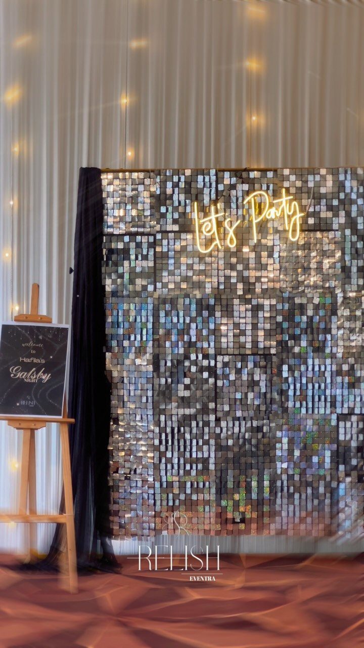 A shimmering sequin party backdrop featuring a glowing neon sign that says Let's Party.