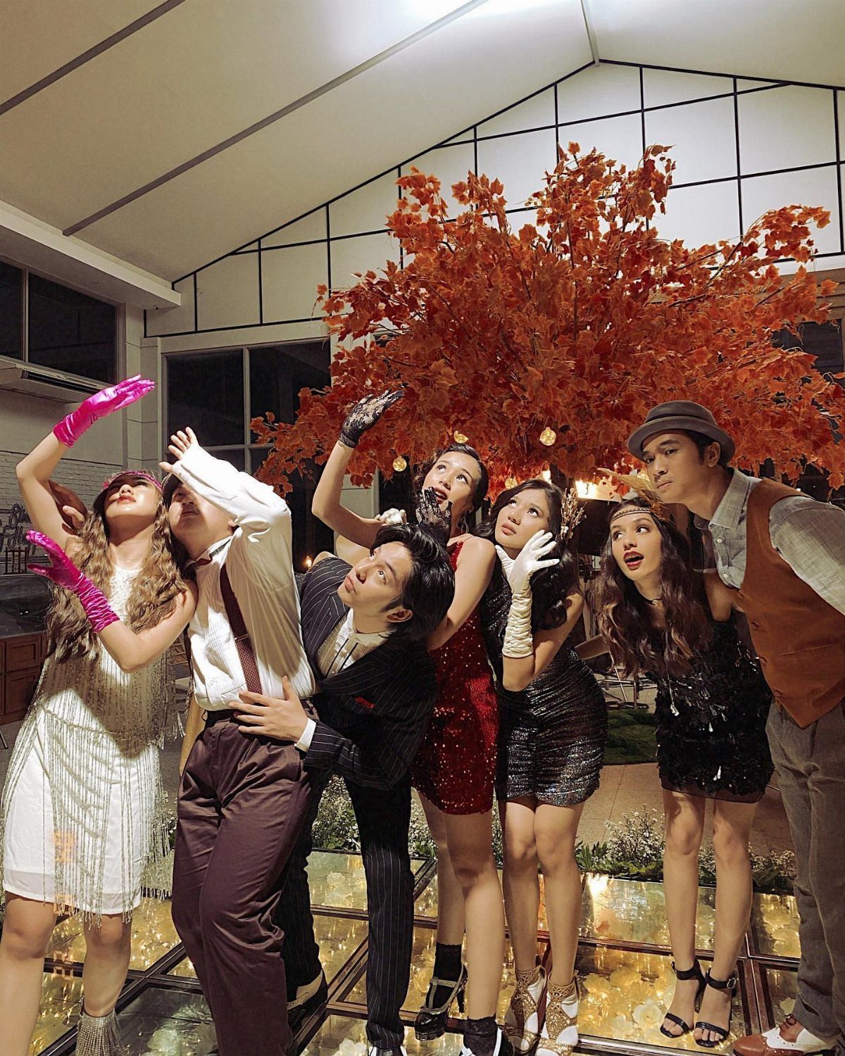People dressed in 1920s flapper and Gatsby-style clothing posing together outdoors at night.