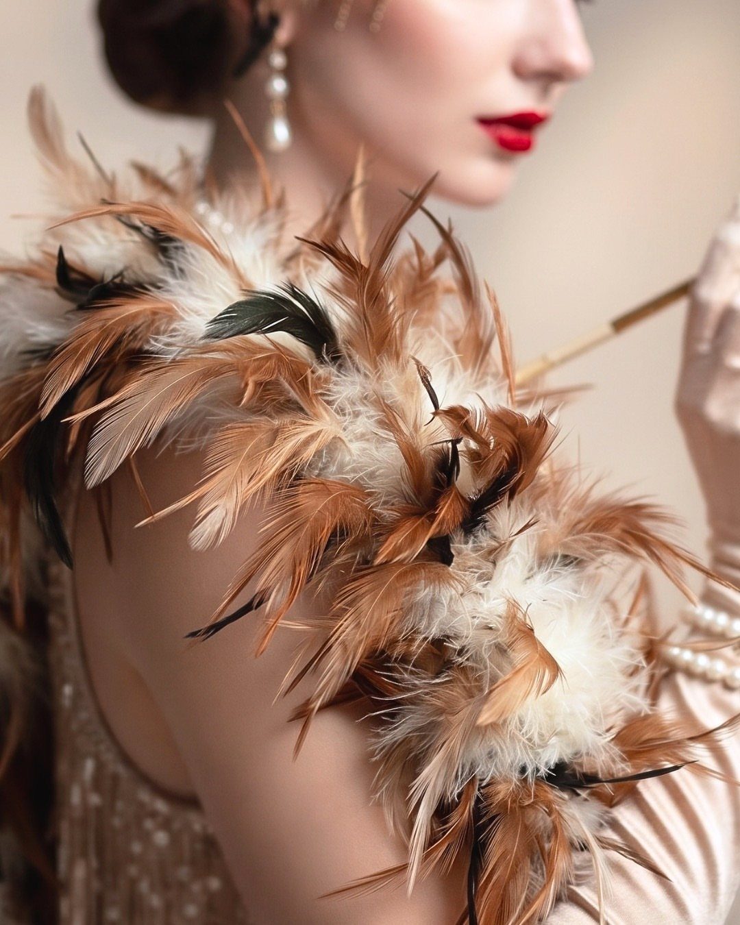 Woman in profile wearing a large brown and cream feather boa and pearl accessories.