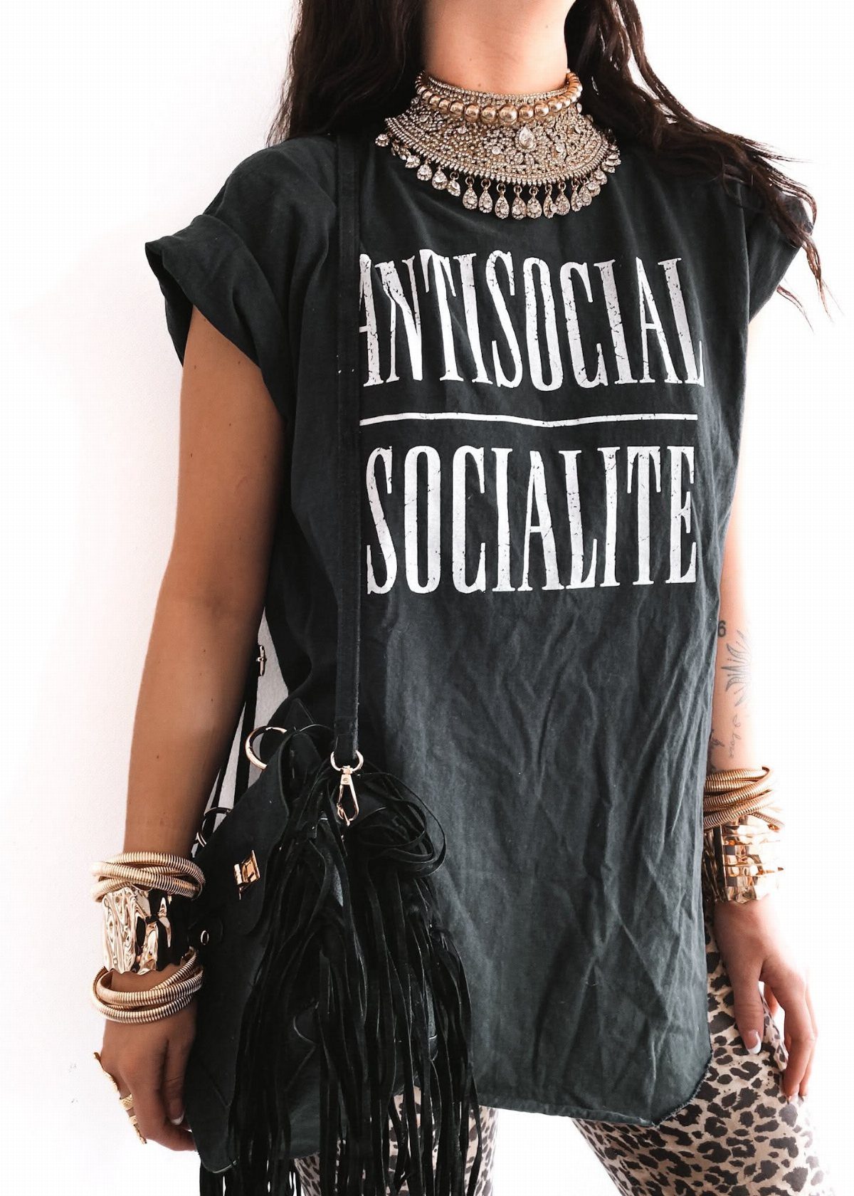 Person wearing a black oversized graphic t-shirt with white text and leopard print pants.
