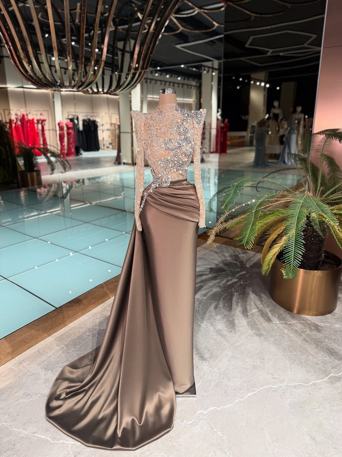 A champagne satin evening gown with a crystal-embellished bodice displayed on a mannequin.