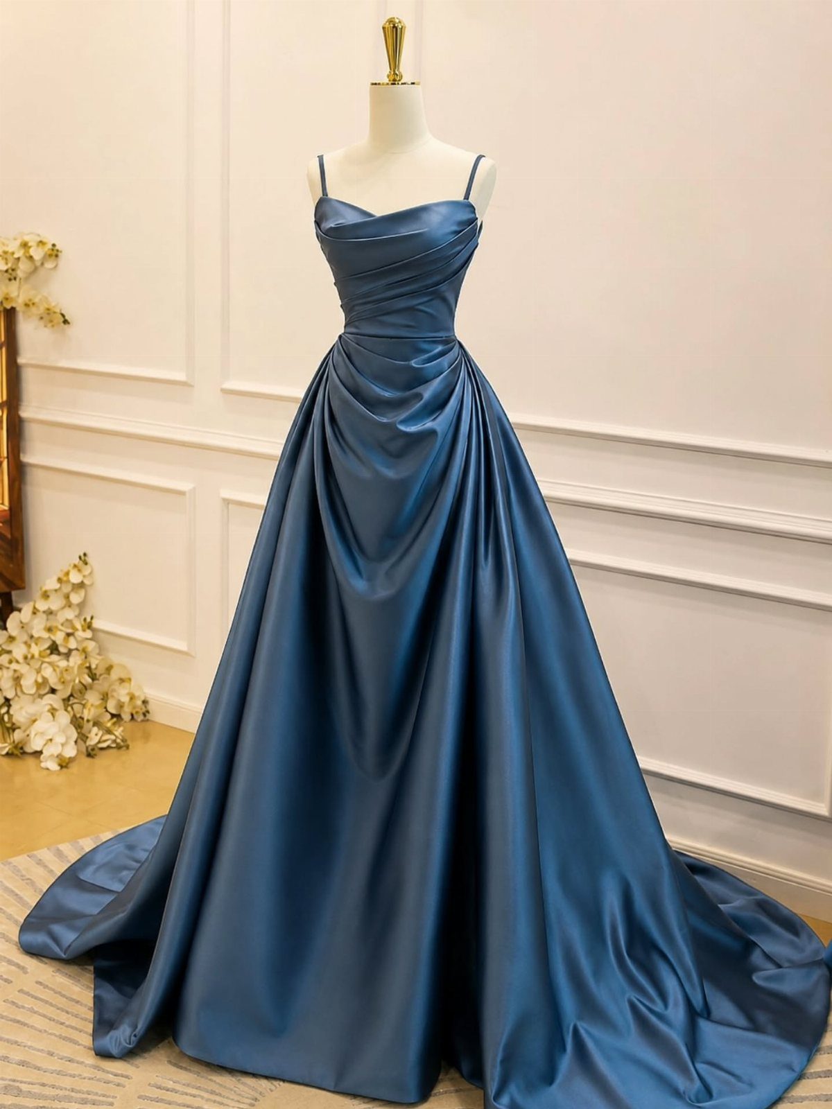 A teal blue satin evening gown with a pleated bodice displayed on a mannequin.