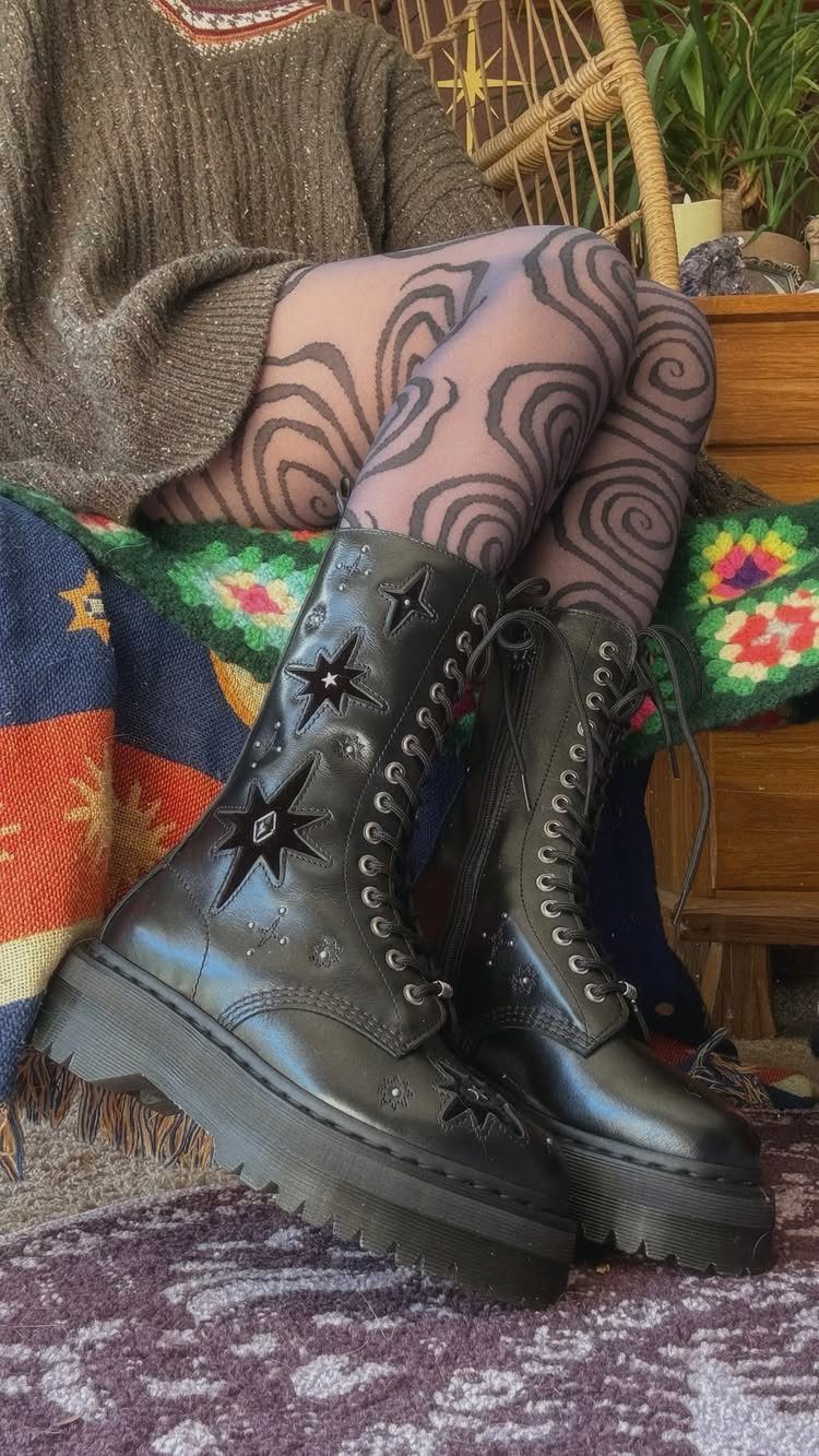 Person wearing patterned tights and black star-embellished combat boots sitting on a colorful blanket.