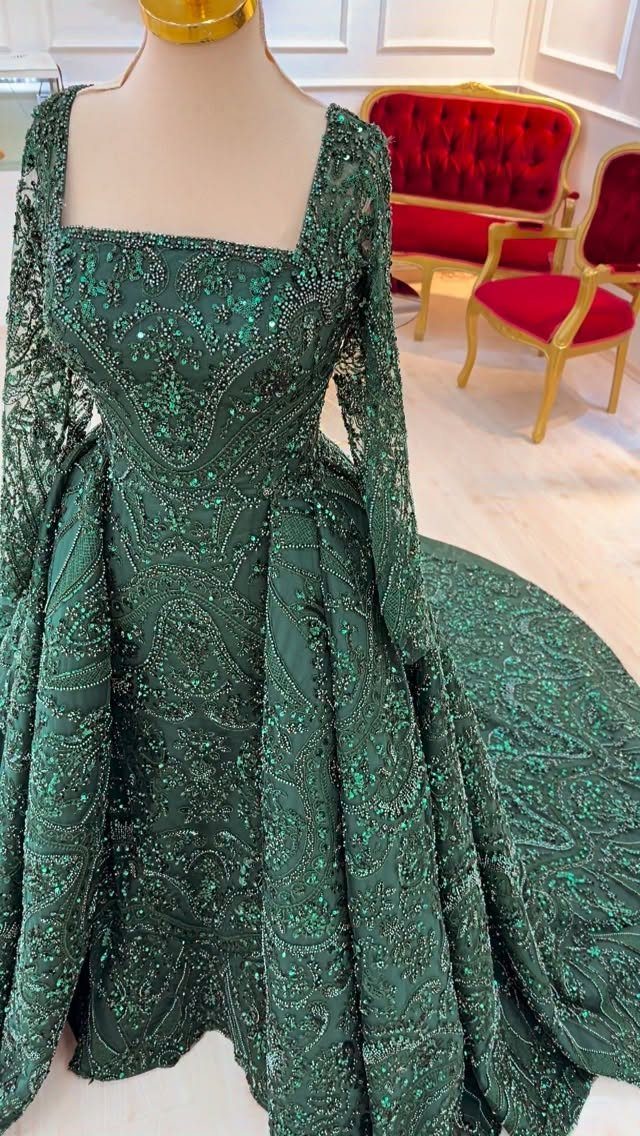 An emerald green sequined ball gown with long sleeves displayed on a mannequin.