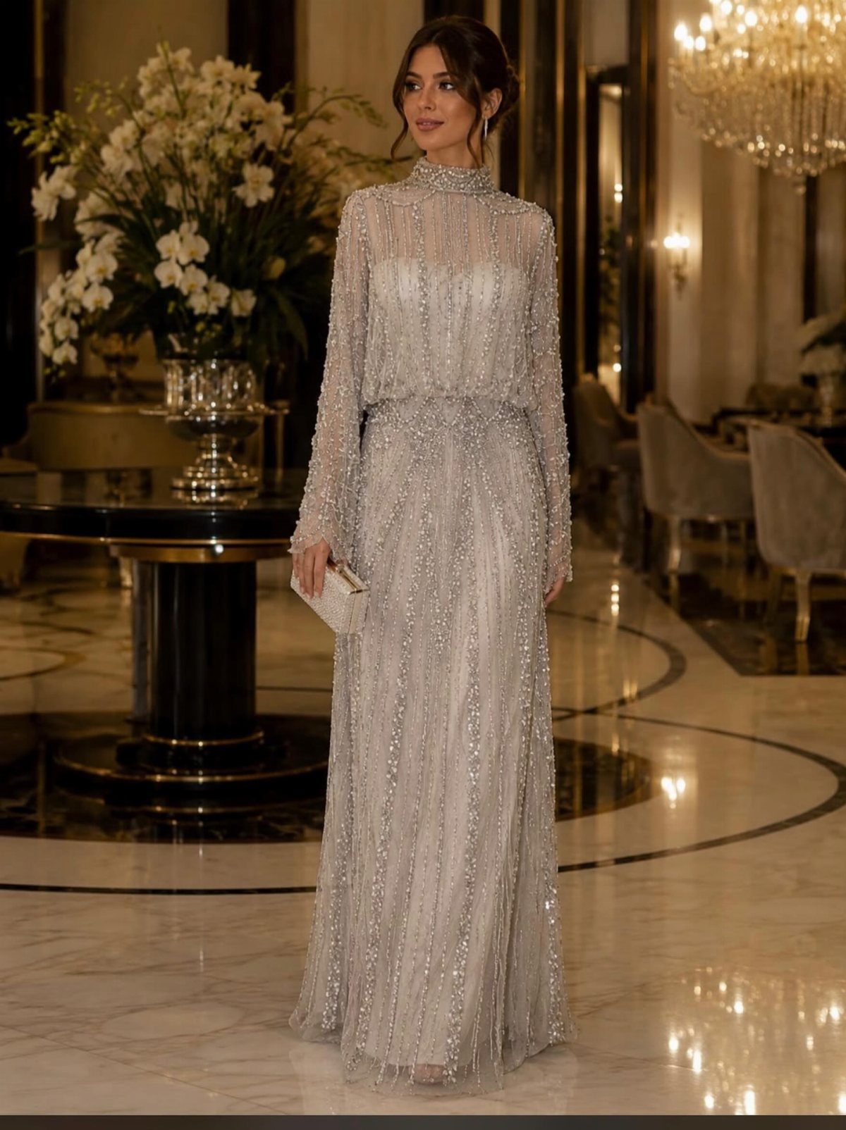 A woman in a shimmering silver long-sleeved A-line dress standing in a grand ballroom.