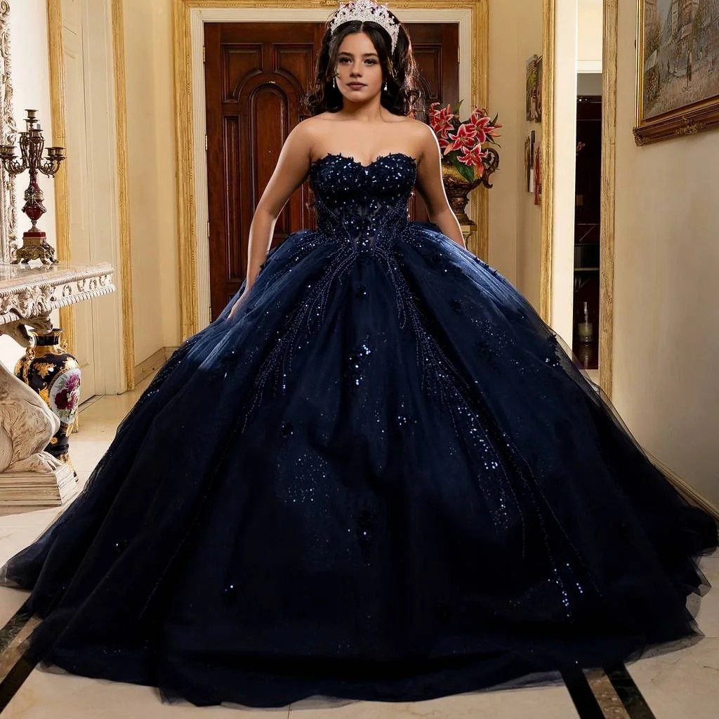A woman in a navy blue ball gown and tiara standing in an elegant room.