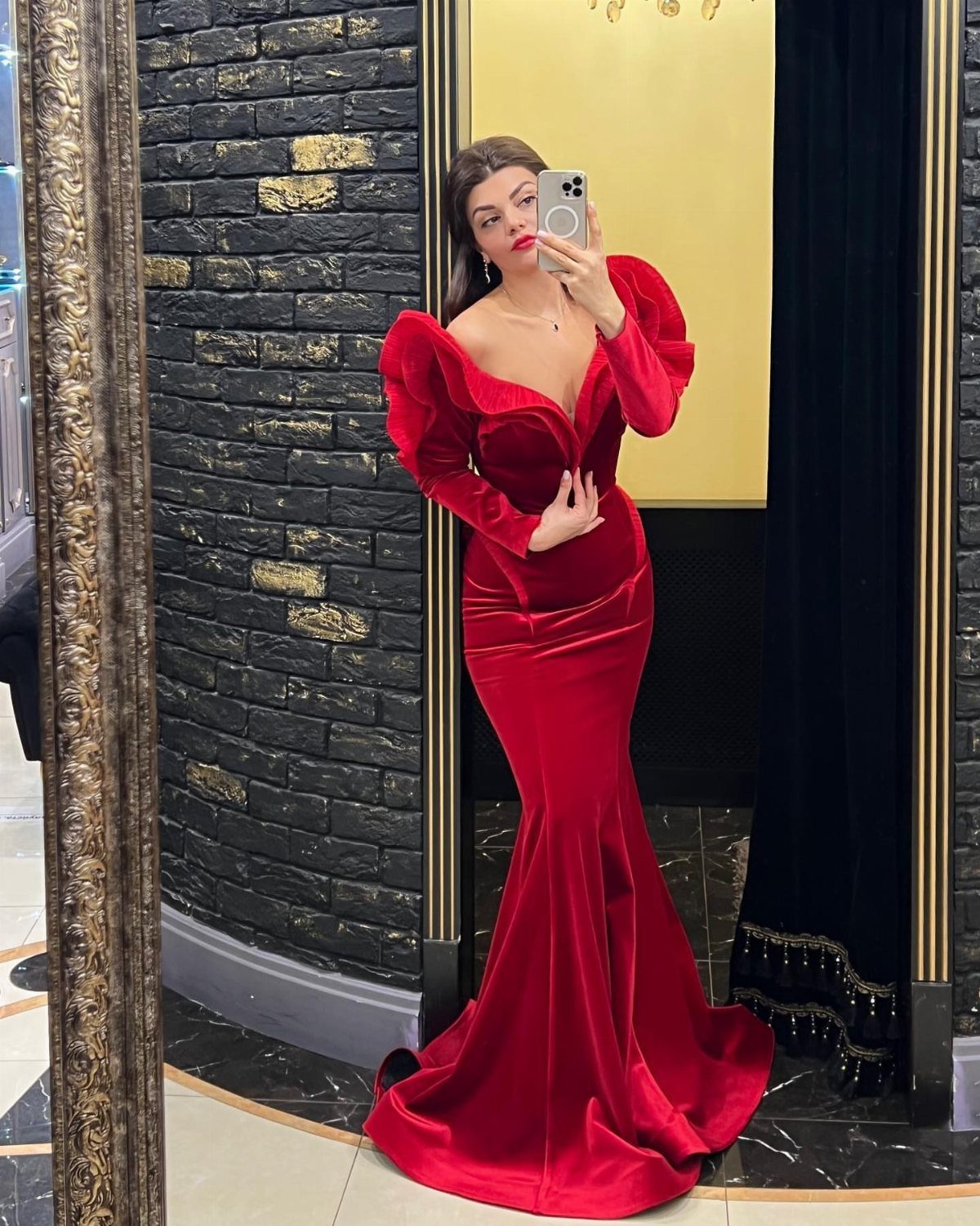 Woman in a red velvet mermaid dress posing for a mirror selfie.