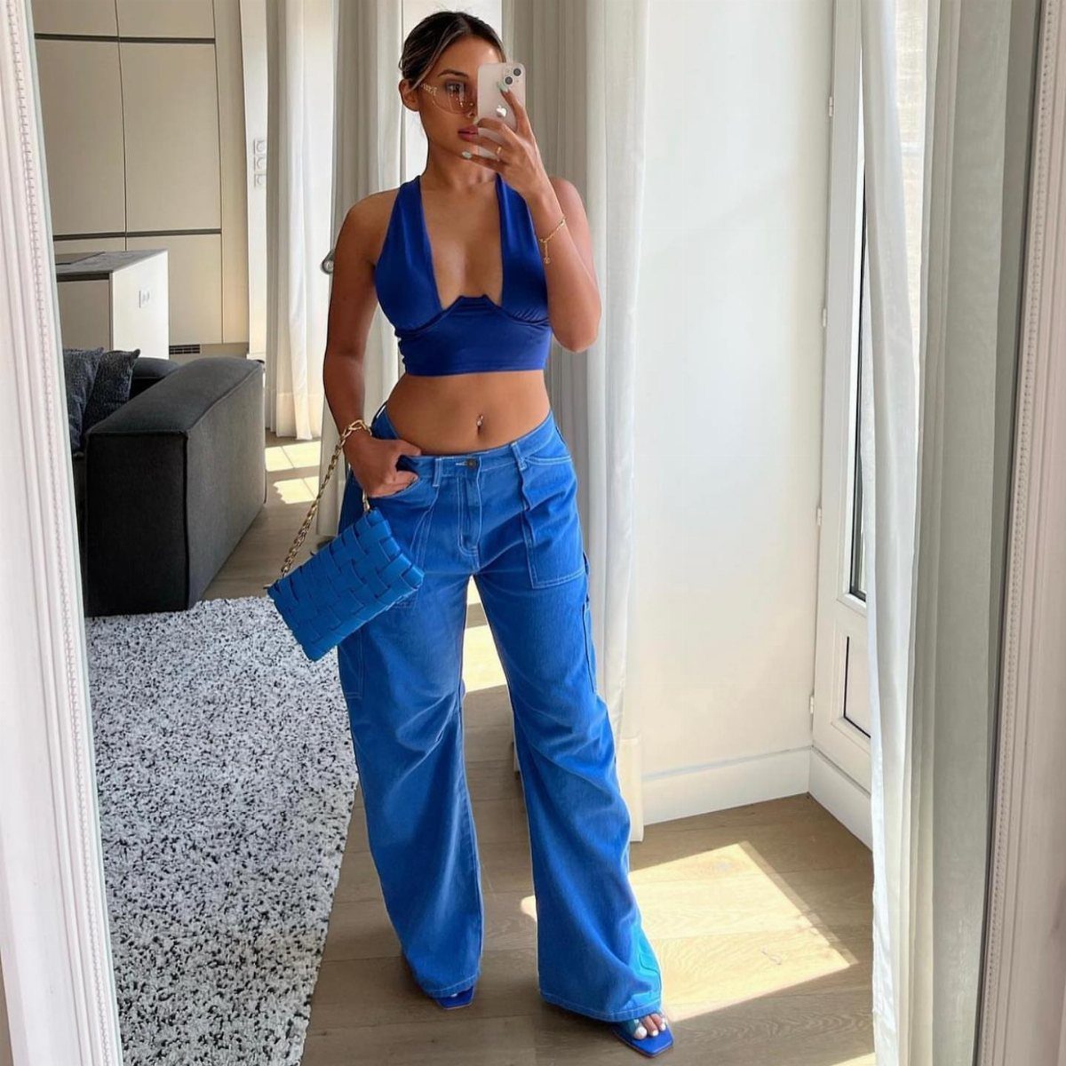 A woman posing in a mirror wearing a bright blue halter top and matching wide-leg trousers.